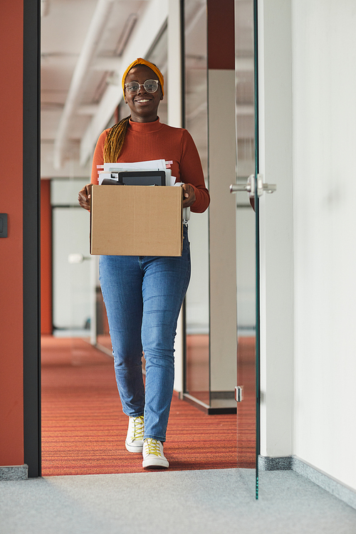 African happy businesswoman carrying box with office stuffs she leaving the office