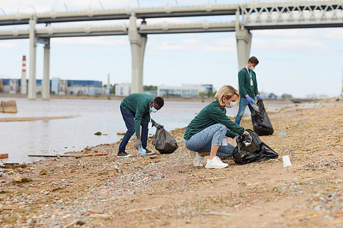 Group of volunteers cleaning the bank of the river from the garbage