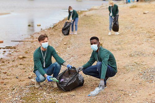 Portrait of young volunteers picking up the garbage into bags they cleaning the sea outdoors
