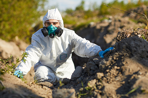 Young woman in protective suit and mask working as ecologist she examining the nature