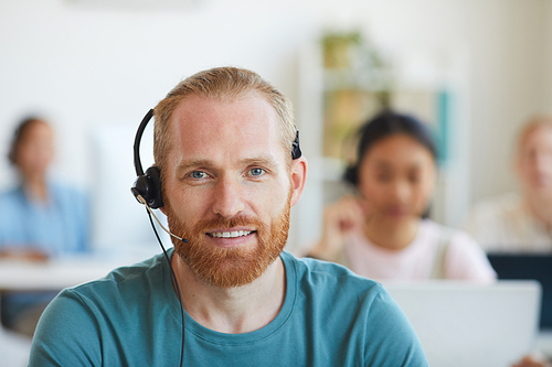 Portrait of bearded man in headphones smiling at camera he working in customer service call center