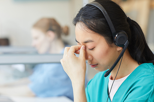 Young woman in headphones tired of work she has a headache while sitting at the table at office
