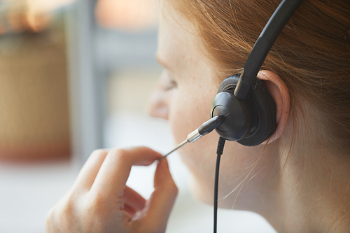Close-up of female operator of call center using headphones to talk to the client