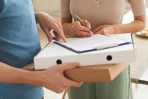 Close-up of woman signing for delivery and taking pizza from delivery man