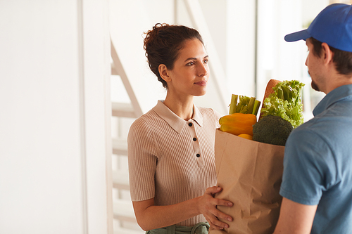 Young woman getting products from delivery man she ordering food at home
