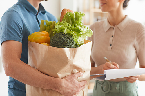 Close-up of man holding products in his hands and delivering food to woman