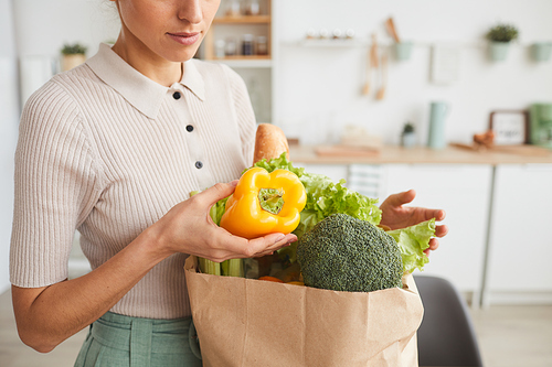 Close-up of woman taking out the fresh vegetables from the paper bag at home