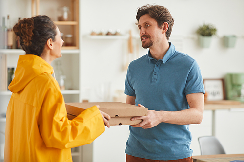 Young woman delivering pizza she standing and delivering pizza to man to home