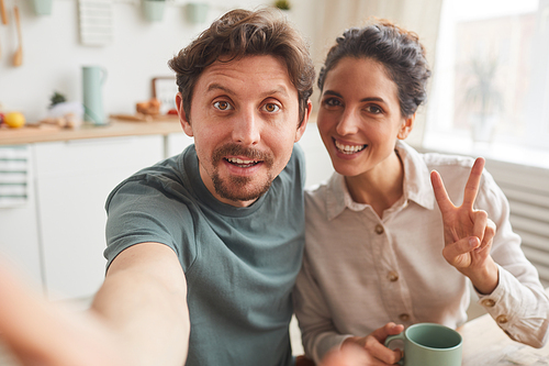 Portrait of happy young couple making selfie portrait during breakfast at home