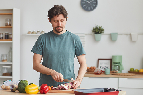 Young man cutting fresh vegetables on cutting board he preparing dinner at home
