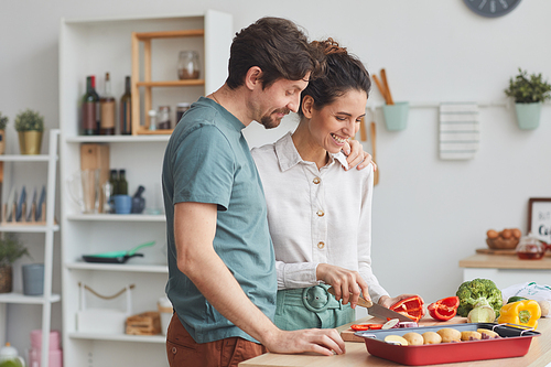Young couple preparing food together in the kitchen they preparing dish from vegetables