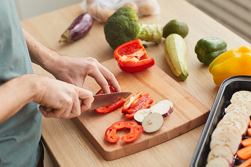 Close-up of man cutting fresh vegetables on cutting board in the kitchen
