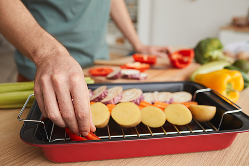 Close-up of man putting cut vegetables on grill he preparing healthy food