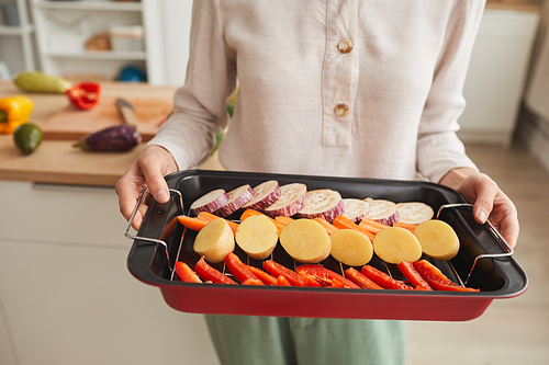 Close-up of woman holding pan with vegetables she preparing grill vegetables