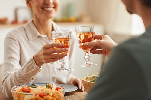 Close-up of young couple having dinner together at the table and toasting with glasses of wine
