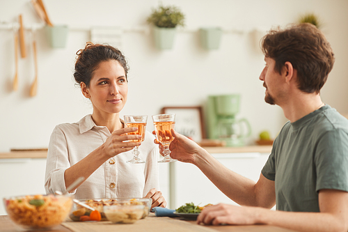 Young couple sitting at the table and celebrating with wine during dinner at home