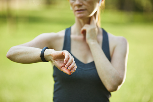 Close-up of sporty woman measuring pulse while checking time after training in park