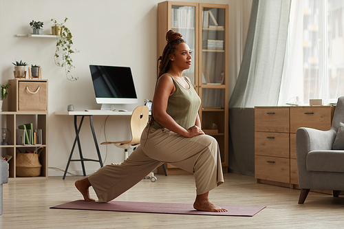 Woman exercising on exercise mat she stretching her legs during sports training at home