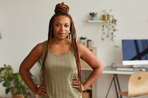 Portrait of African woman with beautiful hairstyle looking at camera while standing in the the room