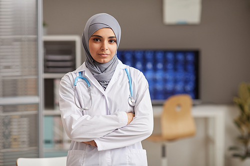 Portrait of muslim doctor in white coat standing with her arms crossed at hospital looking at camera