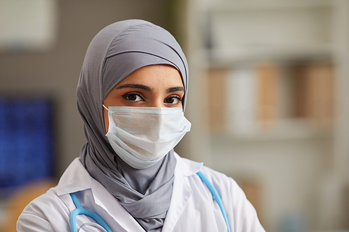 Close-up of muslim female doctor in protective mask looking at camera working at hospital