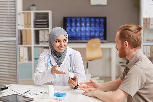 Muslim female doctor telling about the medicine to her patient during his visit at hospital