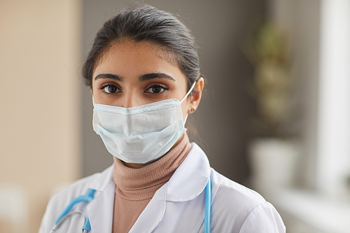 Close-up of nurse in protective mask looking at camera standing at hospital