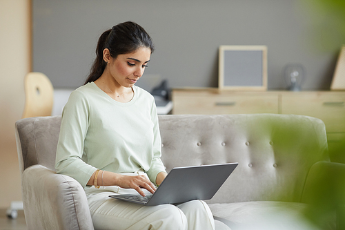 Young woman sitting on sofa and typing on laptop computer she working online at home