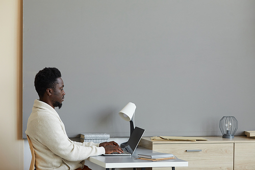 African young man using laptop for online work sitting at his workplace at office