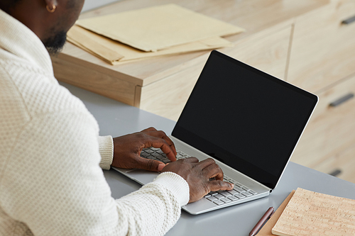 Close-up of African businessman typing on laptop he doing his online work at the table