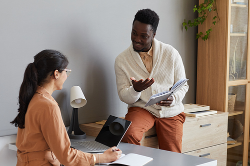 Two business partners discussing work with each other while working in team at office