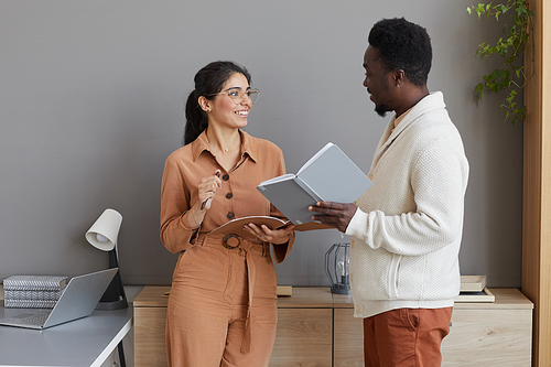 Business partners with notepads in their hands standing at office and discussing new plans