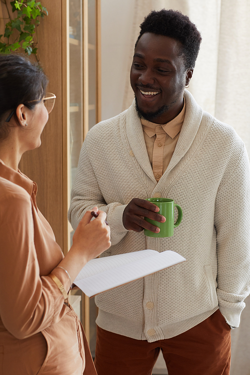 African businessman smiling and discussing business contract with his colleague standing at office