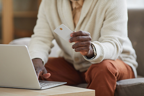 Close-up of African businessman sitting in front of the laptop and paying online with credit card