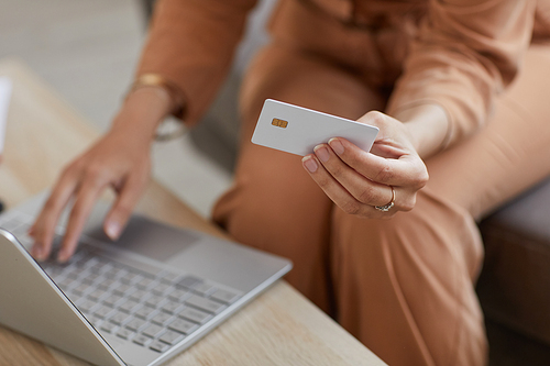 Close-up of woman sitting at the table using laptop and paying online with credit card for purchases