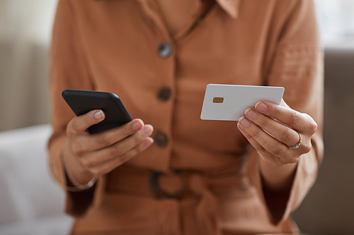 Close-up of woman holding mobile phone and credit card in her hands she paying online for bills