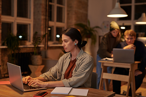 Young businesswoman sitting at the table at office and typing on laptop