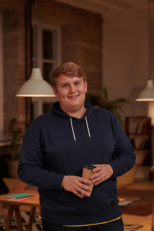 Portrait of young overweight businessman in casual clothing drinking coffee and smiling at camera standing at office