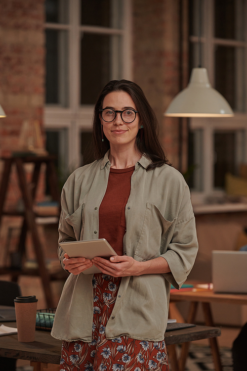 Portrait of young businesswoman in eyeglasses with tablet pc smiling at camera at office