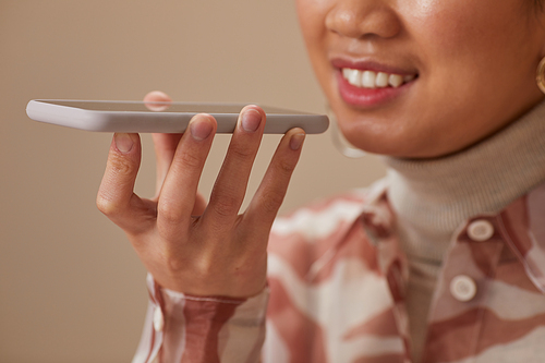 Close-up of woman smiling while recording audio message on her mobile phone