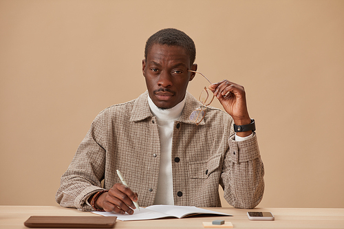 Portrait of African businessman sitting at his workplace looking at camera while doing paper work