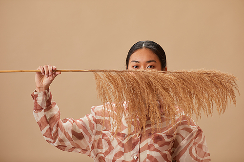 Portrait of Asian young woman posing with plant against the beige background