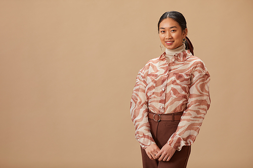 Portrait of Asian beautiful woman in elegant clothing posing against the beige background