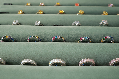 Part of display with rows of luxurious rings between grey velvet holders in contemporary boutique of jewelry