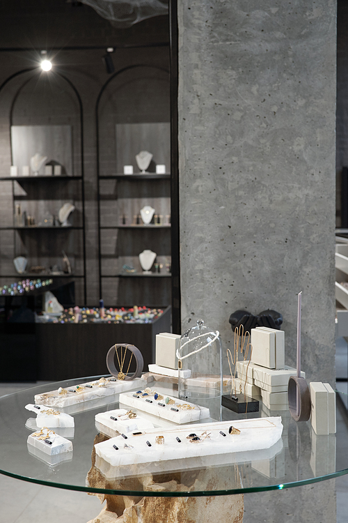 Glass table with new collection of jewelry on background of other displays with necklace assortment in boutique