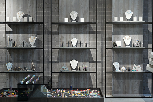 Part of interior of luxury jewelry store or gift shop with necklaces, bracelets, rings and earrings on displays