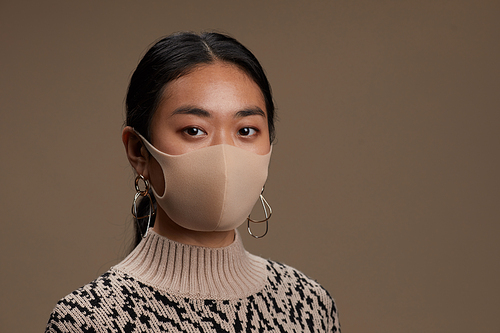 Portrait of Asian young woman posing at camera in protective mask