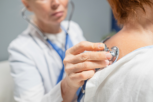 Close-up of doctor examining senior patient with stethoscope at hospital