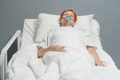 Elderly woman breathing with oxygen mask on her face while she lying in bed at hospital ward