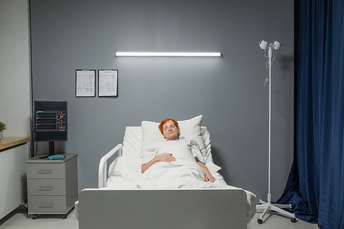 Sick senior woman sleeping in bed at hospital ward during covid epidemic